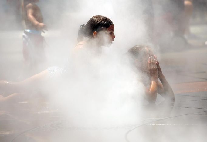 Two girls cool off in the mist from a fountain on the Rose Kennedy Greenway on a hot summer day in Boston, Massachusetts June 21, 2012. A heat wave blanketed the U.S. Mid-Alantic and Northeast Thursday, sparking brownouts in New York City and forcing utilities across the region to ask customers to conserve electricity. REUTERS/Brian Snyder (UNITED STATES - Tags: ENVIRONMENT ENERGY SOCIETY TPX IMAGES OF THE DAY) Published: Čer. 21, 2012, 7:10 odp.