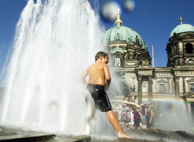 A boy cools off in a fountain in front of the Berlin Cathedral on a hot sunny summer day in Berlin, August 19, 2012. REUTERS/Thomas Peter (GERMANY - Tags: ENVIRONMENT) Pu