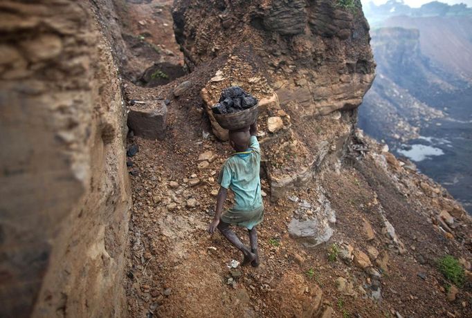 A boy carries coal at an open cast coal field at Dhanbad district in the eastern Indian state of Jharkhand September 20, 2012. With oil and gas output disappointing and hydropower at full throttle, Asia's third-largest economy still relies on coal for most of its vast energy needs. About 75 percent of India's coal demand is met by domestic production and, according to government plans, that won't change over the next five years. Picture taken September 20, 2012. To match INDIA-COAL/ REUTERS/Ahmad Masood (INDIA - Tags: BUSINESS EMPLOYMENT ENERGY SOCIETY ENVIRONMENT) Published: Říj. 21, 2012, 10:01 odp.