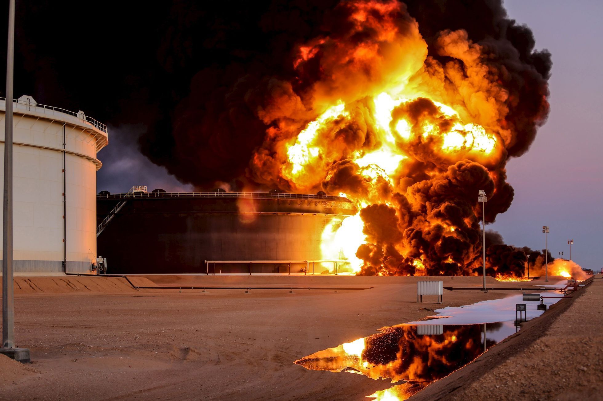 Hořící zásobník ropy po útoku Islámského státu na rafinérii v Rás Lanúfu v Libyi..