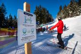 Cedule na Černé hoře vyzývá lyžaře k dodržování protiepidemických opatření.