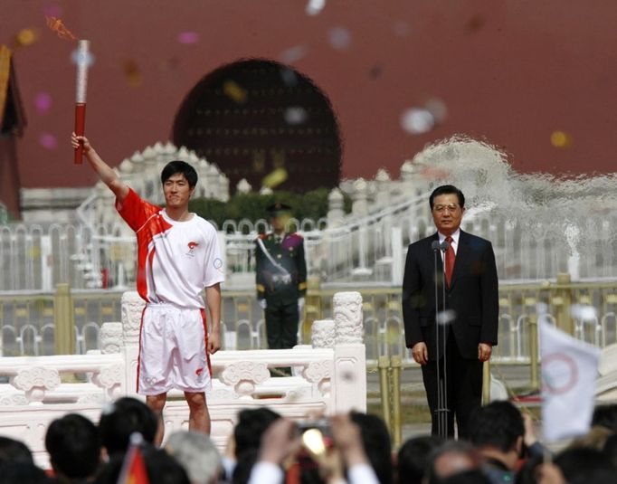 Olympijský běžec přes překážky Liu Xiang pozvedá olympijskou pochodeň.