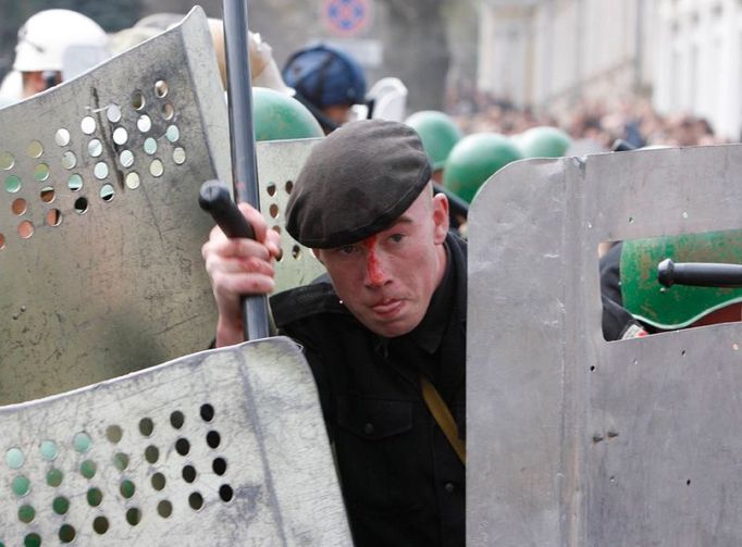 Zraněný policista odráží útok demonstrantů.