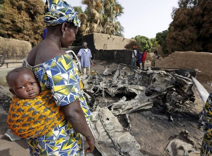 A woman stands near a vehicle, believed to belong to Islamist rebels and destroyed during French air strikes, in the recently liberated town of Diabaly January 24, 2013. REUTERS/Eric Gaillard (MALI - Tags: CIVIL UNREST CONFLICT MILITARY POLITICS) Published: Led. 24, 2013, 6:03 odp.