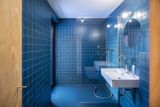 Koupelna je laděná do modré barvy a má podlahu z levné průmyslové gumy.