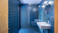 Koupelna je laděná do modré barvy a má podlahu z levné průmyslové gumy.