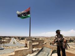 Jeden z rebelů vztyčil vlajku nad městem Kikla, které Kaddáfího vojáci v pondělí opustili.