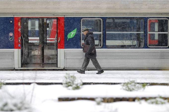 A man walks past a commuter train on a snow-covered platform at the Gare Saint Lazare train station in Paris March 12, 2013 as winter weather with snow and freezing temperatures returns to northern France. REUTERS/Gonzalo Fuentes (FRANCE - Tags: ENVIRONMENT TRANSPORT) Published: Bře. 12, 2013, 2:28 odp.