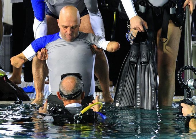 French athlete Philippe Croizon, whose arms and legs were amputated after an electric shock accident in March 1994, is helped by an unidentified divers to enter a 33 metre (36 yard) deep pool, the world's deepest pool built to train professional divers, at Nemo33 diving centre in Brussels January 10, 2013. Croizon, who swam with adapted prostheses that had flippers attached, broke a world record and became the first disabled person to dive to 33 metres, according to the organisers. REUTERS/Yves Herman (BELGIUM - Tags: SOCIETY SPORT DIVING) Published: Led. 10, 2013, 3:49 odp.