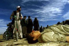 Civilisté obcházejí těla mrtvých bojovníků Talibanu u silnice na Kábul. 13. listopad 2001.