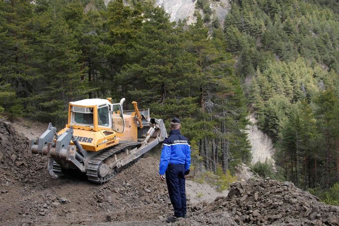 Buldozer "proráží" provizorní cestu k místu neštěstí.