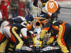 Fernando Alonso se svým Renaultem v péči mechaniků při testech na okruhu Montmelu.