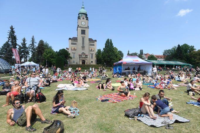 Účastnici hudebního festivalu Mezi ploty v areál Psychiatrická nemocnice Bohnice. V pozadí je vidět věž kostela Svatého Václava. Snímek z roku 2018