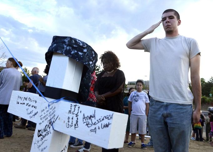 Airman 1st Class Andrew Zayatz salutes a cross with the name of Navy member John Thomas Larimer at the memorial site for the people killed by the gunman in the Century 16 theater, in Aurora, Colorado July 22, 2012. Zayatz serves currently at Peterson Air Force Base in Colorado Springs. REUTERS/Jeremy Papasso (UNITED STATES - Tags: CRIME LAW MILITARY) Published: Čec. 23, 2012, 2:56 dop.