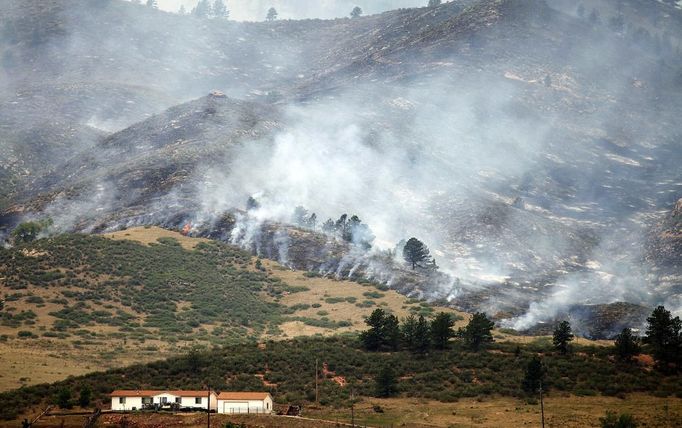 Smoke and flames encroach upon a home on the eastern front of the High Park fire near Laporte, Colorado June 10, 2012. A wind-driven wildfire burning in a rugged Colorado canyon spread out of control, forcing hundreds of people to evacuate and one person in the fire zone was reported missing, officials said on Sunday. REUTERS/Marc Piscotty (UNITED STATES - Tags: DISASTER ENVIRONMENT) Published: Čer. 10, 2012, 9:35 odp.