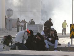 Muži a ženy si v bahrajnské metropoli utírají oči poté, co policie zasáhla slzným plynem.