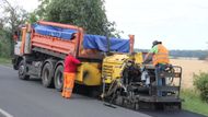 Finišer do vyfrézované díry položí živičnou směs, která má teplotu kolem 300°C.