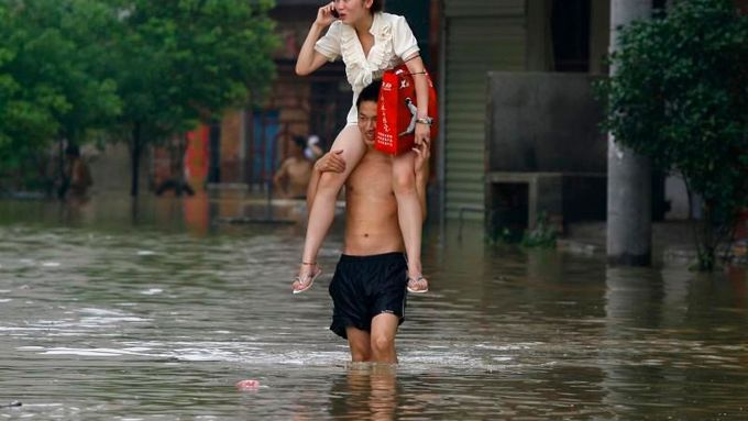 Jak se dostat do práce, když jsou zrovna povodně? V Číně na zádech svého muže.