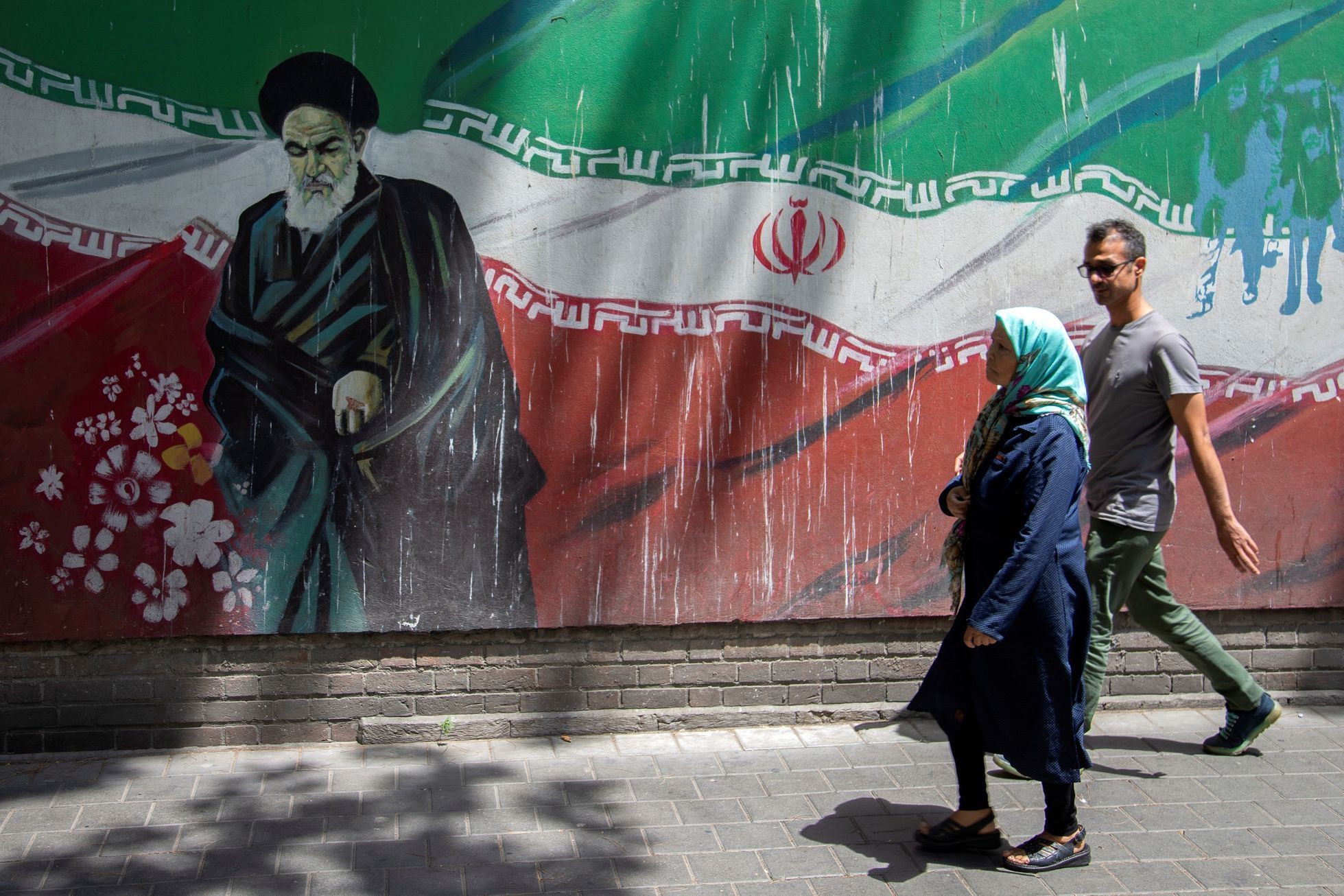 Lidé v Teheránu míjejí malbu někdejšího íránského revolučního vůdce Rúholláha Chomejního.