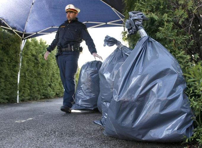 A police officer places bags, at least one of them marked "Spuren" ("evidence"), in the entrance to the backyard of a house in Amstetten in eastern Austria April 30, 2008. Josef F., a 73-year-old electrical engineer, had confessed to holding his daughter captive in the house's basement for 24 years in what Austrian media have branded "The House Of Horrors", police said. REUTERS/Heinz-Peter Bader (AUSTRIA)