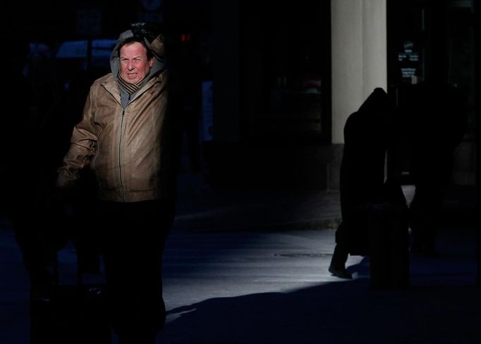 A man grimaces as he adjusts his hood while walking in single digit temperatures on a cold morning in Boston, Massachusetts January 23, 2013. REUTERS/Jessica Rinaldi (UNITED STATES - Tags: ENVIRONMENT SOCIETY) Published: Led. 23, 2013, 3:13 odp.