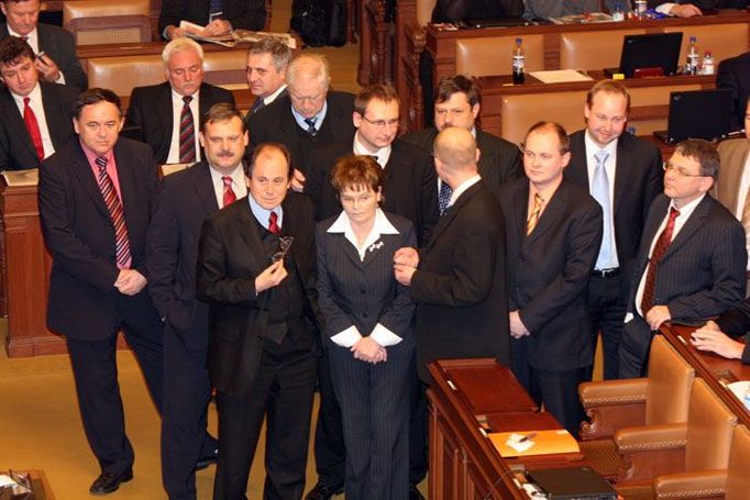 Hlouček poslanců ve stoje poslouchá projev Miloše Melčáka, který je podle jejich slov zrádce.