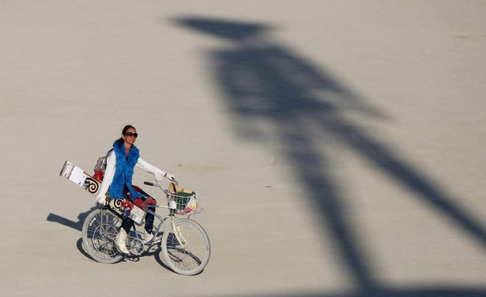 A participant rides past the shadow of the Man during the Burning Man 2012 "Fertility 2.0" arts and music festival in the Black Rock Desert of Nevada, August 29, 2012. More than 60,000 people from all over the world have gathered at the sold out festival, which is celebrating its 26th year, to spend a week in the remote desert cut off from much of the outside world to experience art, music and the unique community that develops.