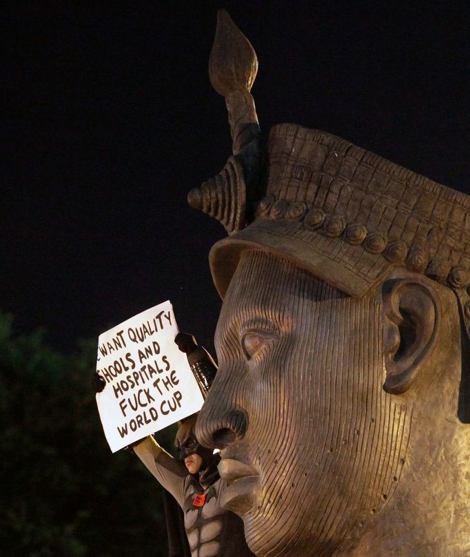 An anti-government demonstrator dressed as comic book character Batman holds a banner atop a monument of former slave Zumbi dos Palmares during a protest against 2014 Wor