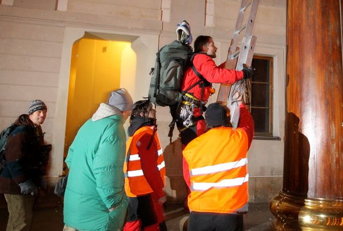 Horolezec začíná stoupat po žebříku na sloup na prvním nádvoří Pražského hradu. Greenpeace věděli, že s potleskem posádky na Hradě počítat nemohou.