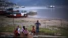 A family sits near a shipyard in Fengjie, on the banks of the Yangtze River, 170km (105 miles) from the Three Gorges dam, Chongqing province August 7, 2012. China relocated 1.3 million people during the 17 years it took to complete the Three Gorges dam. Even after finishing the $59 billion project last month, the threat of landslides along the dam's banks will force tens of thousands to move again. It's a reminder of the social and environmental challenges that have dogged the world's largest hydroelectric project. While there has been little protest among residents who will be relocated a second time, the environmental fallout over other big investments in China has become a hot-button issue ahead of a leadership transition this year. Picture taken on August 7, 2012. To match story CHINA-THREEGORGES/ REUTERS/Carlos Barria (CHINA - Tags: POLITICS ENVIRONMENT BUSINESS ENERGY) Published: Srp. 22, 2012, 8:26 odp.