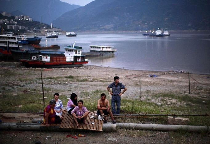 A family sits near a shipyard in Fengjie, on the banks of the Yangtze River, 170km (105 miles) from the Three Gorges dam, Chongqing province August 7, 2012. China relocated 1.3 million people during the 17 years it took to complete the Three Gorges dam. Even after finishing the $59 billion project last month, the threat of landslides along the dam's banks will force tens of thousands to move again. It's a reminder of the social and environmental challenges that have dogged the world's largest hydroelectric project. While there has been little protest among residents who will be relocated a second time, the environmental fallout over other big investments in China has become a hot-button issue ahead of a leadership transition this year. Picture taken on August 7, 2012. To match story CHINA-THREEGORGES/ REUTERS/Carlos Barria (CHINA - Tags: POLITICS ENVIRONMENT BUSINESS ENERGY) Published: Srp. 22, 2012, 8:26 odp.