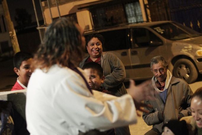 People laugh as Catholic priest Adolfo Huerta, known as "Gofo", conducts a mass outside a house in a neighbourhood in Saltillo February 26, 2013. Ordained five years ago, Huerta is an unconventional priest who likes rock music, dyes the ends of his hair red, dresses in black, and enjoys riding his motorcycle. Huerta found God and priesthood while studying philosophy at the Pontifical University in Mexico City and working with HIV-positive patients and sex workers as a social activist. He says it is important to demystify faith and accept people's differences without judgment, and in his sermons he references rock songs, quotes books and tells jokes. Picture taken February 26, 2013. REUTERS/Daniel Becerril (MEXICO - Tags: RELIGION SOCIETY) ATTENTION EDITORS: PICTURE 14 OF 26 FOR PACKAGE 'CHURCH, FAITH AND ROCK'N ROLL' SEARCH 'PRIEST DANIEL' FOR ALL IMAGES Published: Bře. 15, 2013, 10:23 dop.