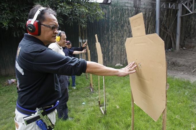 Jaime "Jimmy" Santiago (L), a lower court judge in Manila, with his fellow court judges checks their target cardboard during their shooting practice at a police firing range in Manila March 6, 2013. Santiago, a former police officer who headed a special weapons and tactics (SWAT) unit, favours arming Filipino judges to protect themselves from disgruntled litigants who can't accept decisions and criminal syndicates whose members were sent to jail. There had been cases of shootings inside courtrooms. In photo from L-R: Judge court Jaime Santiago, Judge court Emilio Legazpi III, Judge coourt Jose Lorenzo Dela Rosa and Judge court Armando Yanga. Picture taken March 6, 2013. REUTERS/Romeo Ranoco (PHILIPPINES - Tags: POLITICS CRIME LAW) Published: Dub. 4, 2013, 11:22 dop.