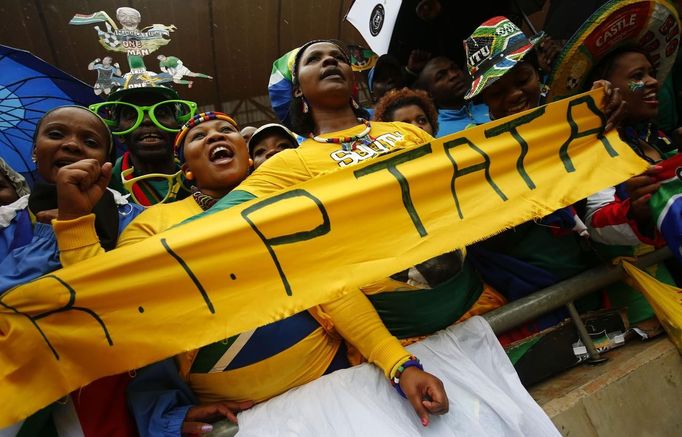 People sing and dance in heavy rain while waiting for the start of the official memorial service for late South African President Nelson Mandela at the First National Bank stadium, also known as Soccer City, in Johannesburg December 10, 2013.