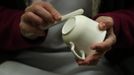 A worker uses a polishing stone to remove rough edges on a partially fired cup in the "biscuit room" at the Middleport pottery in Stoke-on-Trent, central England January 22, 2013. The pottery which dates back to 1888 and was rescued from closure in 2009, continues to use traditional methods to produce its range of ceramics and famous Burleigh Ware pottery. REUTERS/Phil Noble (BRITAIN - Tags: BUSINESS EMPLOYMENT SOCIETY) Published: Led. 22, 2013, 5:27 odp.