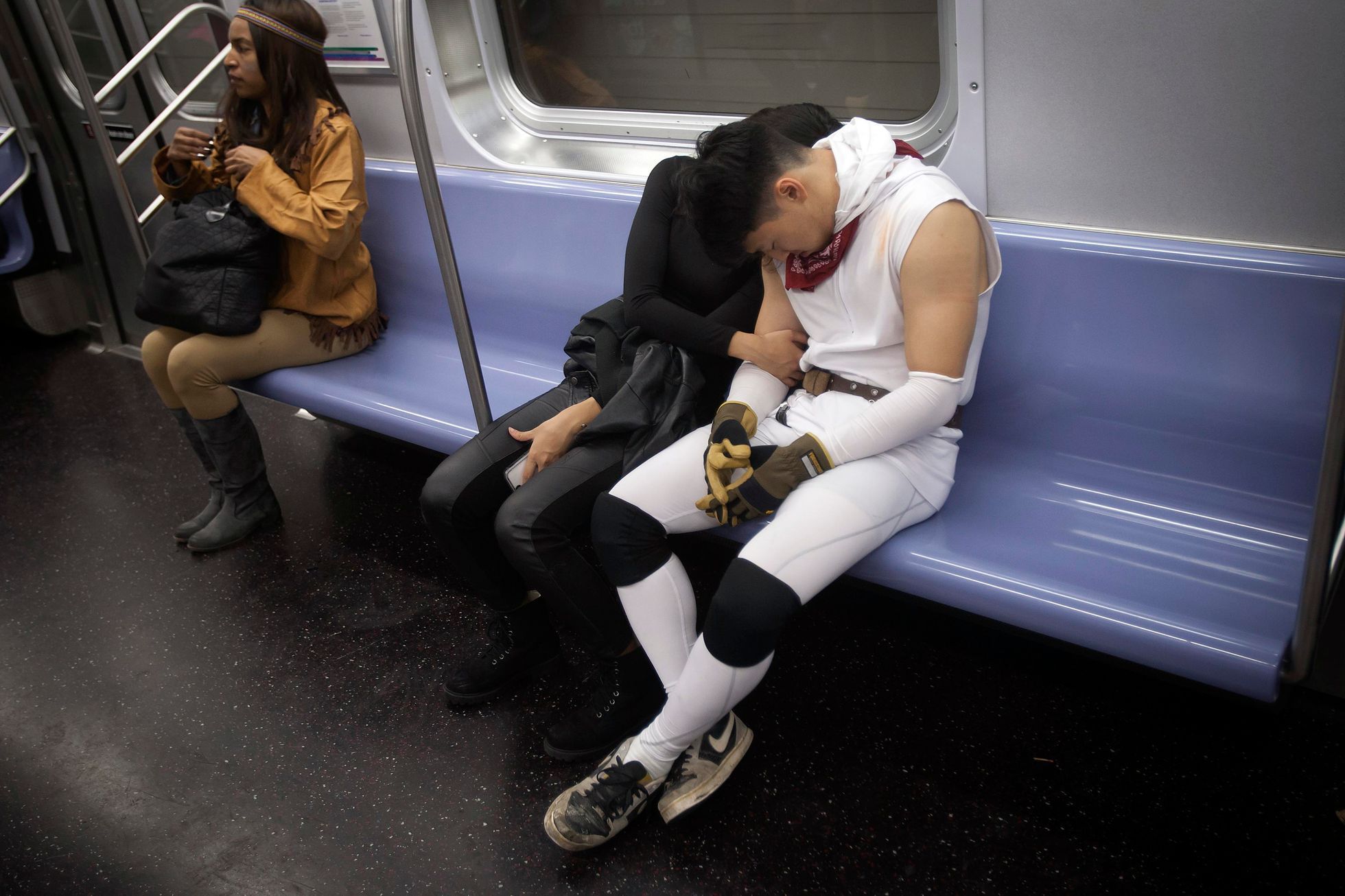 Halloween revellers sleep on the uptown 6 subway train early in the morning in the Manhattan borough of New York