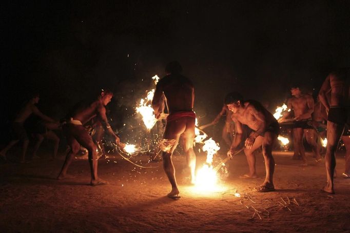 Yawalapiti men use fire and straw to perform a ceremony between cousins during the celebration of this year's 'quarup,' a ritual held over several days to honour in death a person of great importance to them, in the Xingu National Park, Mato Grosso State, August 14, 2012. This year the Yawalapiti tribe honoured two people - a Yawalapiti Indian who they consider a great leader, and Darcy Ribeiro, a well-known author, anthropologist and politician known for focusing on the relationship between native peoples and education in Brazil. Picture taken August 14, 2012. REUTERS/Ueslei Marcelino (BRAZIL - Tags: SOCIETY ENVIRONMENT) FOR EDITORIAL USE ONLY. NOT FOR SALE FOR MARKETING OR ADVERTISING CAMPAIGNS. ATTENTION EDITORS - PICTURE 10 OF 37 FOR THE PACKAGE 'THE YAWALAPITI QUARUP RITUAL' Published: Srp. 29, 2012, 10:20 dop.