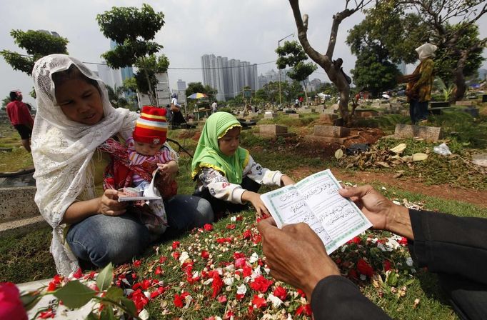 A family reads verses from the Koran at a relative's grave in a cemetery, a day before the Islamic holy month of Ramadan, in Jakarta July 9, 2013. Traditionally Indonesian Muslims will visit the graves of their relatives before and towards the end of the the holy month. REUTERS/Enny Nuraheni (INDONESIA - Tags: RELIGION SOCIETY) Published: Čec. 9, 2013, 8:57 dop.