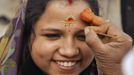 A woman gets her forehead painted by a Hindu priest to welcome the year 2013 on the banks of the river Ganges in the northern Indian city of Allahabad January 1, 2013. REUTERS/Jitendra Prakash (INDIA - Tags: ANNIVERSARY RELIGION SOCIETY) Published: Led. 1, 2013, 7:45 dop.