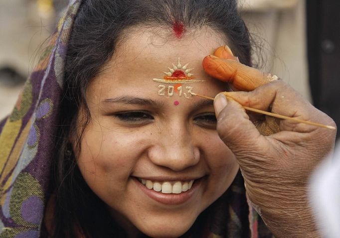 A woman gets her forehead painted by a Hindu priest to welcome the year 2013 on the banks of the river Ganges in the northern Indian city of Allahabad January 1, 2013. REUTERS/Jitendra Prakash (INDIA - Tags: ANNIVERSARY RELIGION SOCIETY) Published: Led. 1, 2013, 7:45 dop.