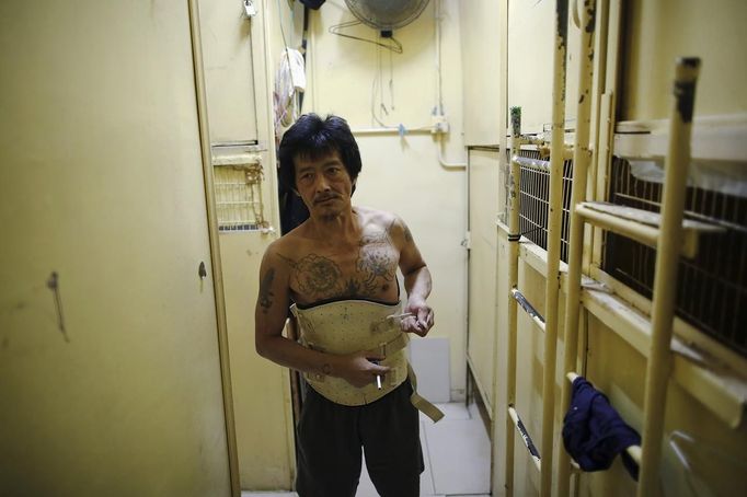 Kam Chung, 49, adjusts his brace between wooden boxes people use for living in Hong Kong October 9, 2012. In Hong Kong's middle-class residential area, short distance from its shopping and financial districts, 24 people live in these wooden boxes, or "coffin homes", packed in a single apartment of little over 50 square meters. Its residents pay 1450 Hong Kong dollars ($180) for their living space built of wooden panels of 2 meters by 70 cm. To maximize income from the rent in central Hong Kong landlords build "coffin homes", nicknamed due to their resemblance to real coffins. Space has always been at a premium in Hong Kong where developers plant high-rises on every available inch. REUTERS/Damir Sagolj (CHINA - Tags: SOCIETY REAL ESTATE BUSINESS) Published: Říj. 9, 2012, 1:57 odp.