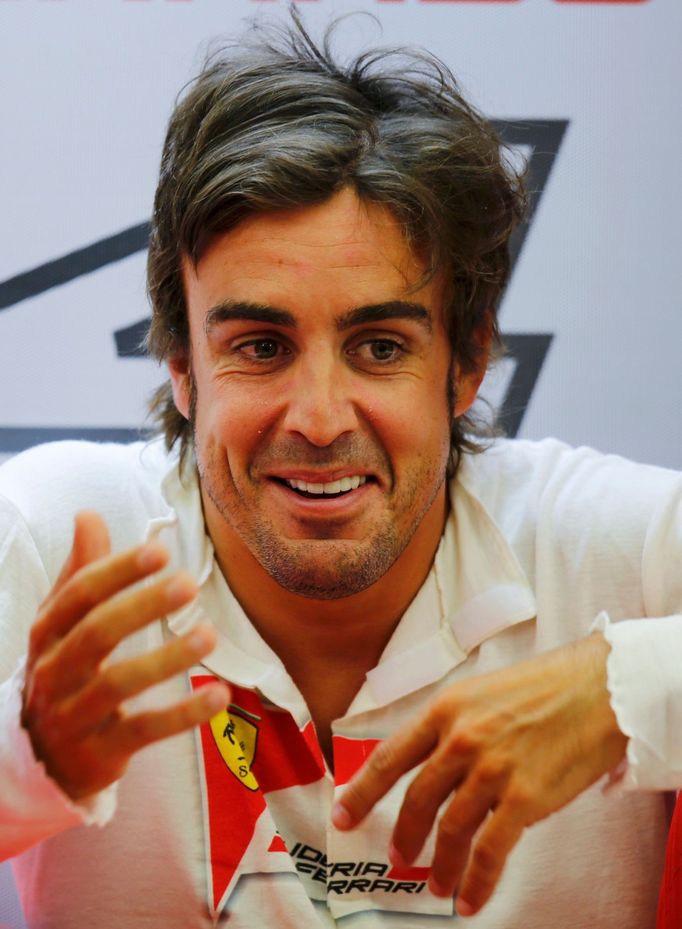 Ferrari Formula One driver Fernando Alonso of Spain speaks with a crew member in his garage during the second practice session of the Bahrain F1 Grand Prix at the Bahrain