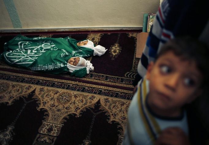 A Palestinian boy stands next to the bodies of Jumana Abu Sefan, 18 months old, and her brother Tamer, three and a half years old, during their funeral at a mosque in the northern Gaza Strip November 18, 2012. The two siblings were killed in an Israeli air strike on Sunday, hospital officials said. Israel bombed militant targets in Gaza for a fifth straight day on Sunday, launching aerial and naval attacks as its military prepared for a possible ground invasion, though Egypt saw "some indications" of a truce ahead. REUTERS/Mohammed Salem (GAZA - Tags: CIVIL UNREST MILITARY POLITICS CONFLICT)