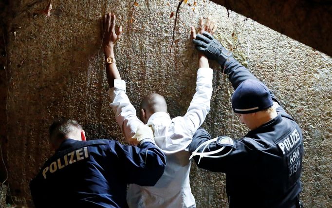 Němečtí policisté prohledávají zadrženého muže.