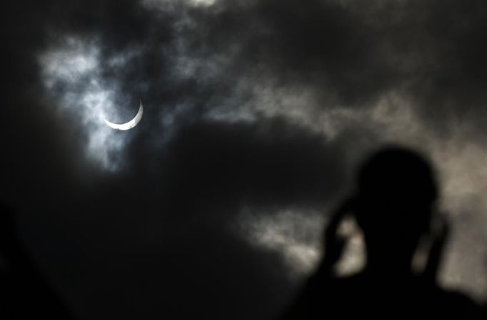 A tourist watches as the moon passing in front of the sun as it approaches a full solar eclipse in the northern Australian city of Cairns November 14, 2012. REUTERS/Tim Wimborne (AUSTRALIA - Tags: SOCIETY ENVIRONMENT) Published: Lis. 13, 2012, 9:39 odp.