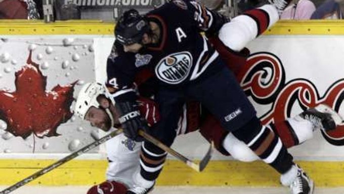 Edmontonský útočník Ryan Smyth (v nodrém) atakuje u hrazení Aarona Warda z Caroliny.