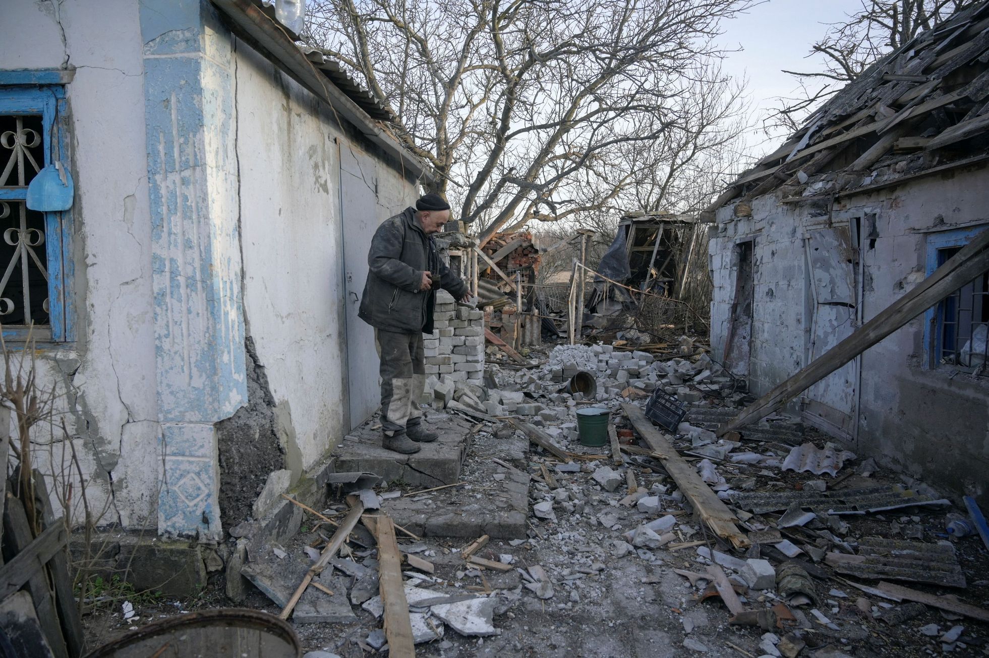 Místní obyvatel Valerij (63) ukazuje budovu, která byla podle něj poškozena nedávným ostřelováním ve vesnici Taramčuk v Doněcké oblasti.
