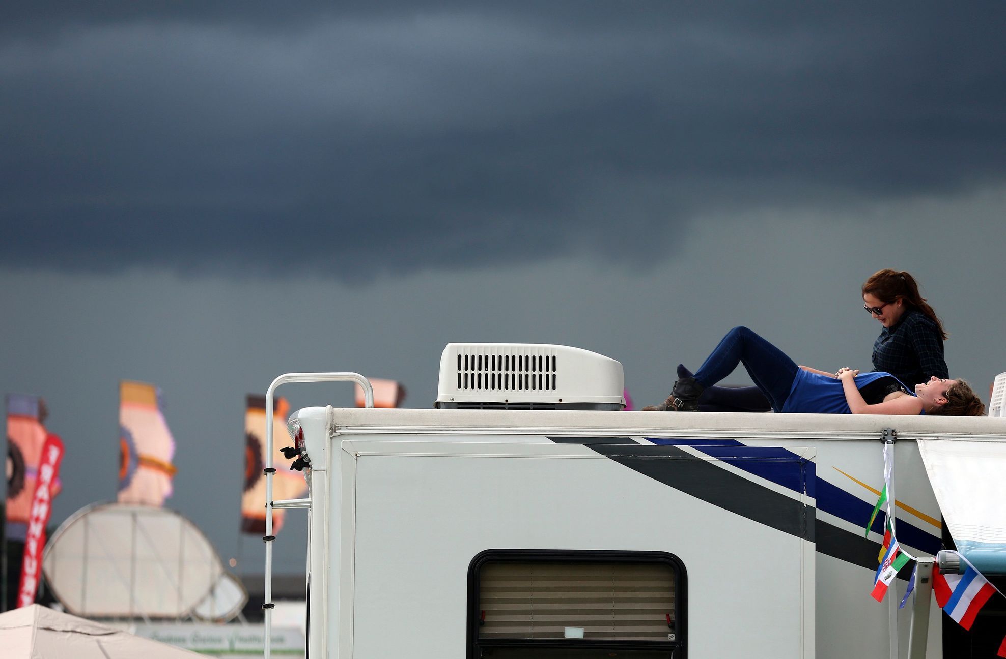 People rest on the roof of a motor home as storm clouds gather at Worthy Farm in Somerset, during the Glastonbury Festival