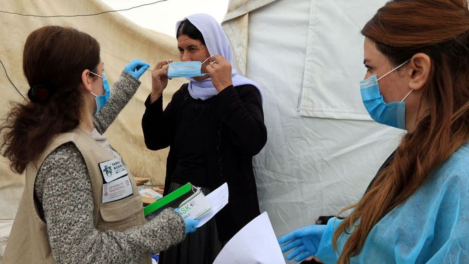Jezídka v iráckém uprchlickém táboře si nasazuje roušku kvůli koronaviru - ilustrační foto.