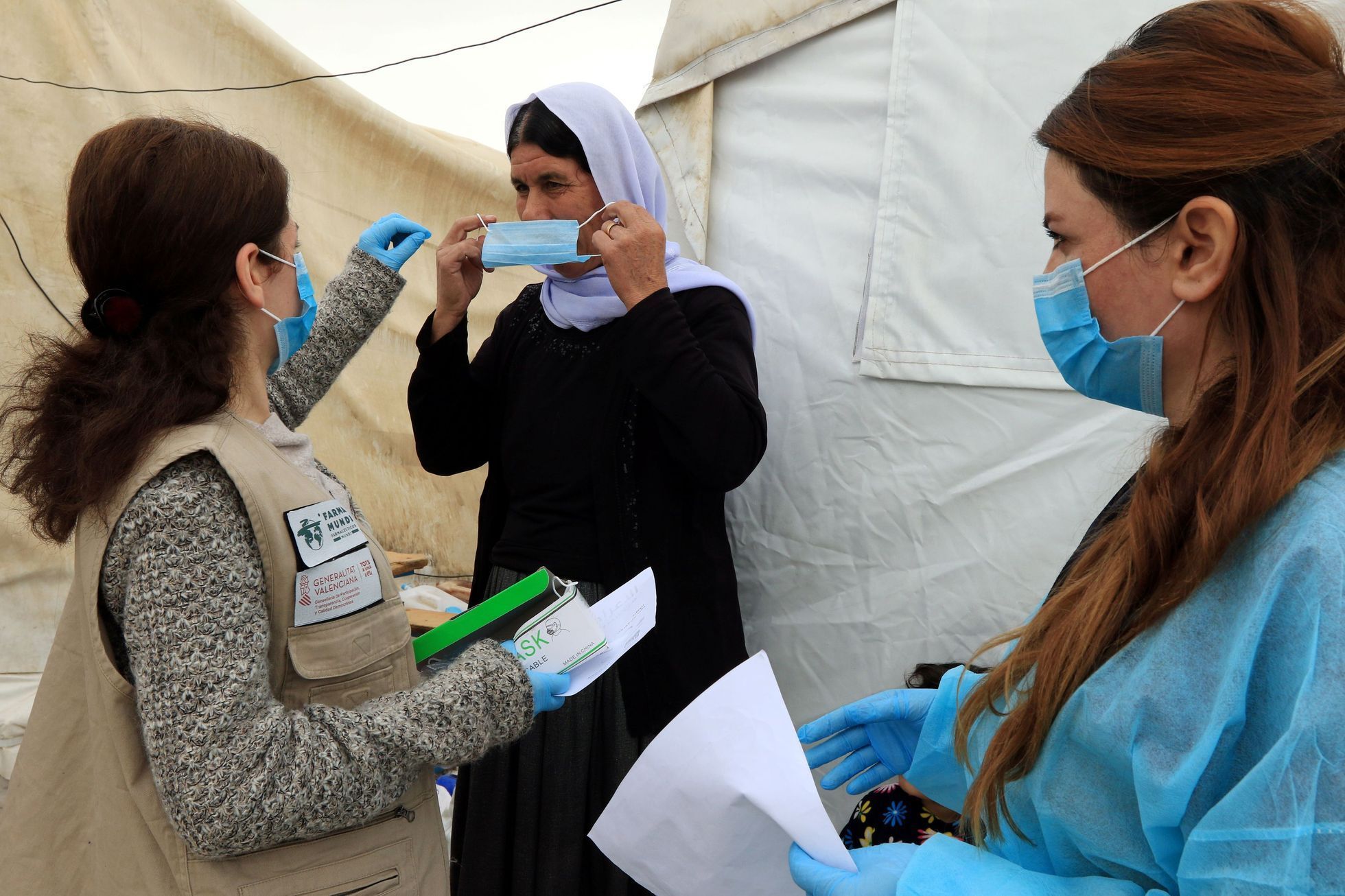 Jezídka v iráckém uprchlickém táboře si nasazuje roušku kvůli koronaviru.
